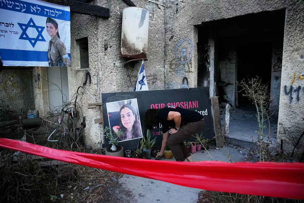 A woman places a candle at a tribute for Ofir Shoshani during a memorial marking two years since the deadly Hamas cross-border attack on Israel, in Kibbutz Kfar Aza, Tuesday, Oct. 7, 2025. (AP Photo/Ohad Zwigenberg)