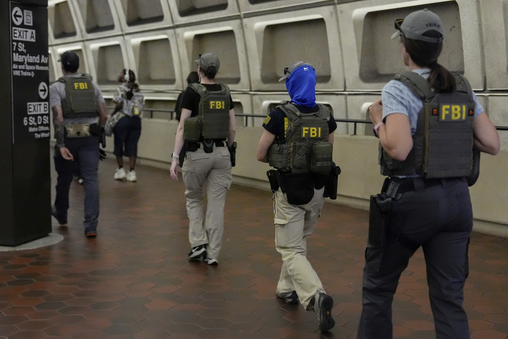 FBI agents follow District of Columbia Metro Transit Police Department and Washington Metropolitan Police Department officers as they escort three people out of L'Enfant Plaza metro station, Thursday, Aug. 21, 2025, in Washington. (AP Photo/Julia Demaree Nikhinson)