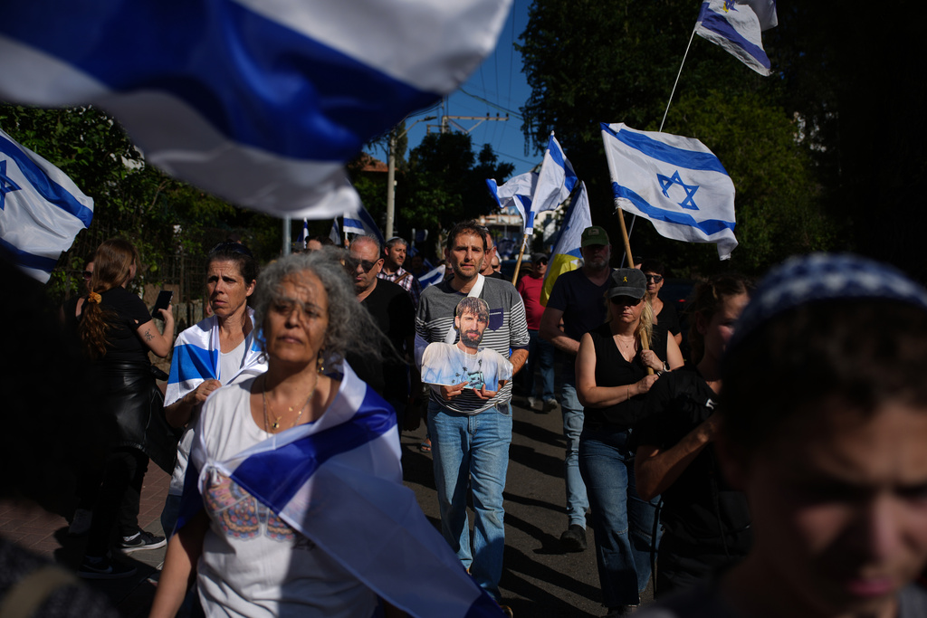 Mourners gather near the car carrying the coffin of slain hostage Guy Illouz during his funeral procession in Rishon Lezion, Israel, Wednesday, Oct. 15, 2025. Illouz remains were returned from Gaza to Israel as part of a ceasefire agreement between Israel and Hamas. (AP Photo/Emilio Morenatti)