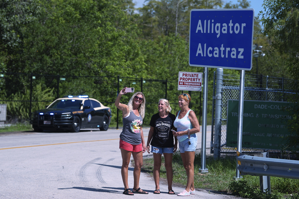 A group of women pose for a selfie in front of the "Alligator Alcatraz" sign at the entrance to an immigration detention center in the Florida Everglades, Thursday, Aug. 28, 2025, in Collier County, Fla. (AP Photo/Rebecca Blackwell)