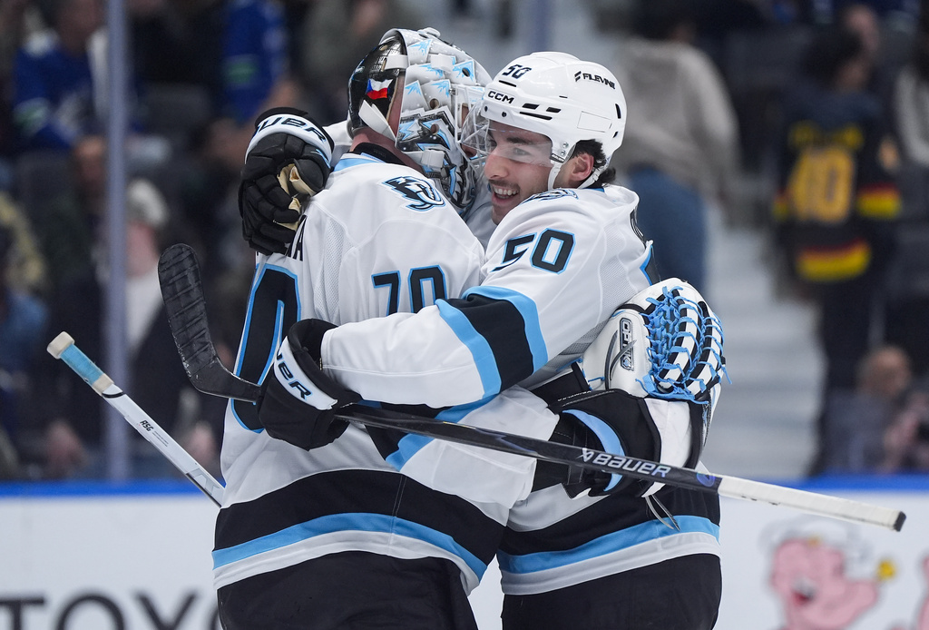 Utah Mammoth's Sean Durzi (50) and goalie Karel Vejmelka (70) celebrate after Utah defeated the Vancouver Canucks in an NHL hockey game, in Vancouver, British Columbia, Saturday, April 4, 2026. (Darryl Dyck/The Canadian Press via AP)