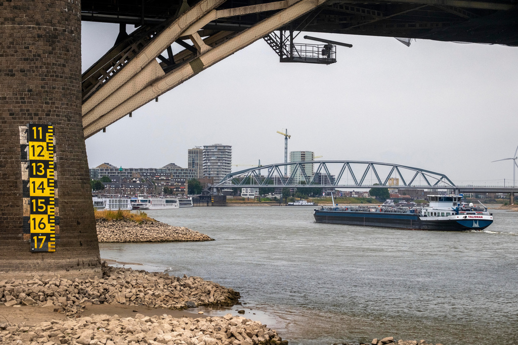 A barge passes under a bridge on the Lek river near Beusichem, Netherlands, Thursday, July 30, 2026, due to drought conditions. (AP Photo/Patrick Post)