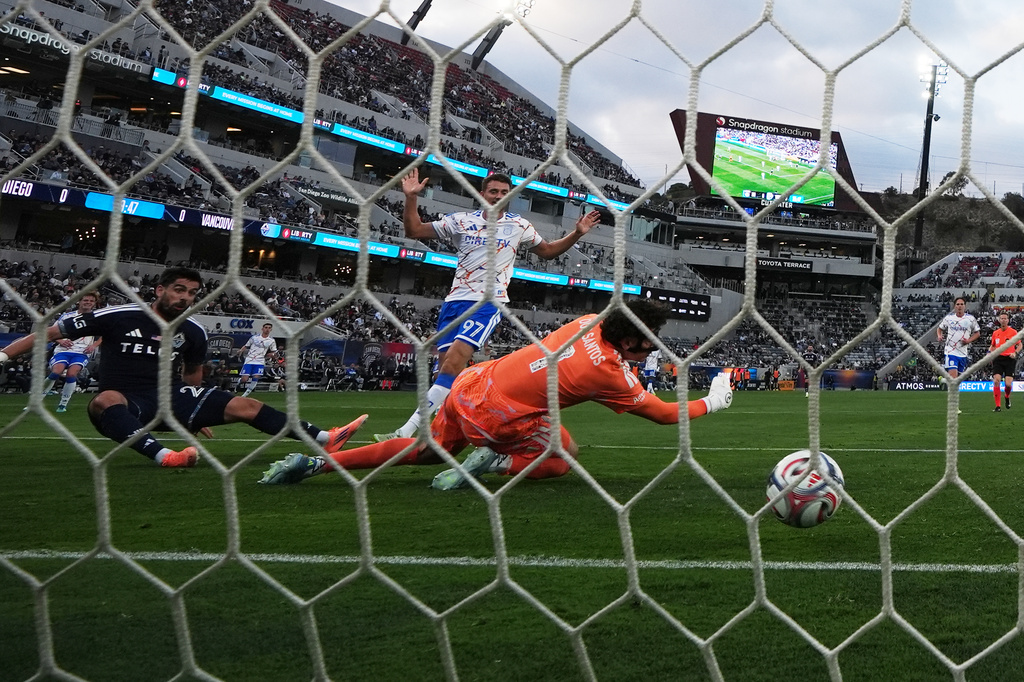 Vancouver Whitecaps FC forward Brian White, left, scores a goal past San Diego FC goalkeeper CJ Dos Santos (1) as defender Christopher McVey (97) looks on during the first half of an MLS soccer match Saturday, May 23, 2026, in San Diego. (AP Photo/Gregory Bull)