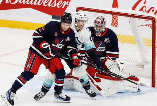 Winnipeg Jets' Vladislav Namestnikov (7) defends against Seattle Kraken's Matty Beniers (10) in front of goaltender Connor Hellebuyck (37) during first period NHL action in Winnipeg on Thursday, Oct. 23, 2025. (John Woods/The Canadian Press via AP) Winnipeg Jets' Vladislav Namestnikov (7) defends against Seattle Kraken's Matty Beniers (10) in front of goaltender Connor Hellebuyck (37) during first period NHL action in Winnipeg on Thursday, Oct. 23, 2025. (John Woods/The Canadian Press via AP)