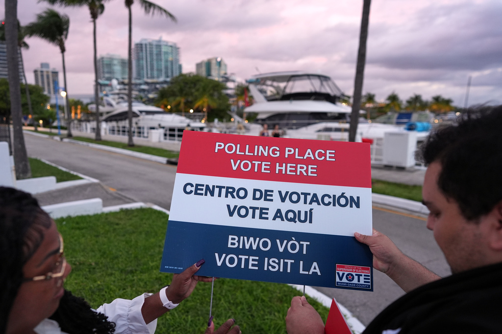 Polling place supervisor Bridget Knighton, left, shows poll worker Steve Delgado how to assemble a sign as they prepare ahead of the opening of a voting site at Miami City Hall, on Election Day, Tuesday, Nov. 4, 2025, in Miami. (AP Photo/Rebecca Blackwell)