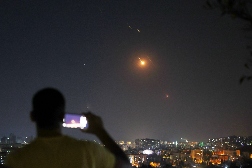 FILE — A man takes a cellphone photo as missiles fired from Iran toward Israel fly over Syrian territory in Damascus, Syria, early Wednesday, June 18, 2025. (AP Photo/Ghaith Alsayed, File)