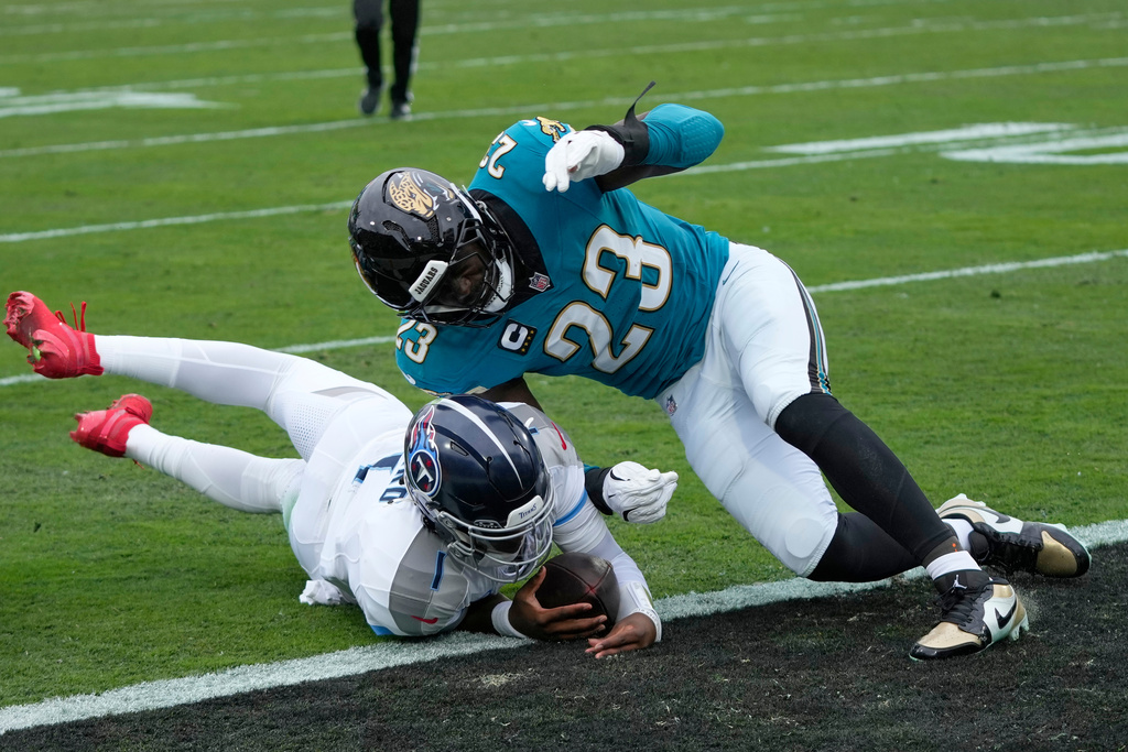 Tennessee Titans quarterback Cam Ward (1) scores a touchdown as he is hit by Jacksonville Jaguars linebacker Foyesade Oluokun (23) during the first half of an NFL football game Sunday, Jan. 4, 2026, in Jacksonville, Fla. (AP Photo/John Raoux)