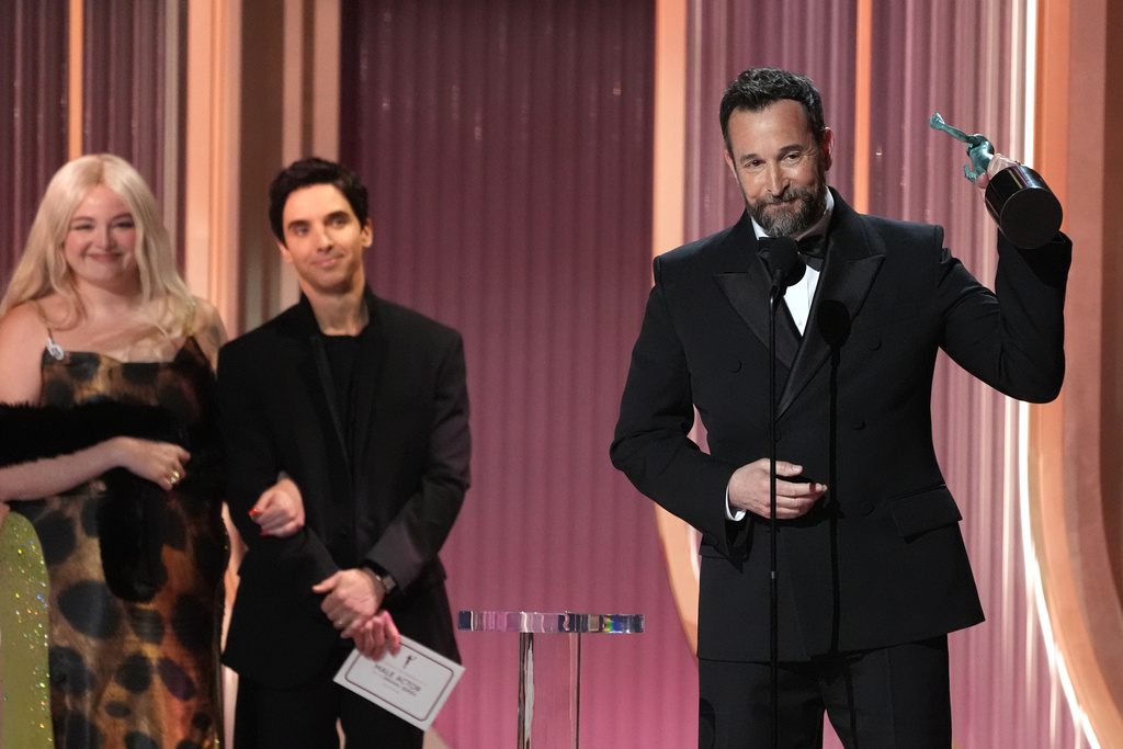 Noah Wyle, right, accepts the award for outstanding performance by a male actor in a drama series for "The Pitt" during the 32nd Annual Actor Awards on Sunday, March 1, 2026, at the Shrine Auditorium and Expo Hall in Los Angeles. Megan Stalter, far left, and Paul W. Downs loook on from left.(AP Photo/Chris Pizzello)