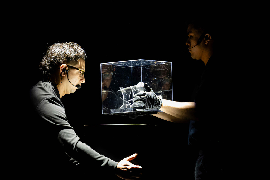 A worker moves a microphone used by Charlie Kirk at Utah Valley University on the day he was fatally shot during Turning Point USA's AmericaFest 2025, Thursday, Dec. 18, 2025, in Phoenix. (AP Photo/Jon Cherry)