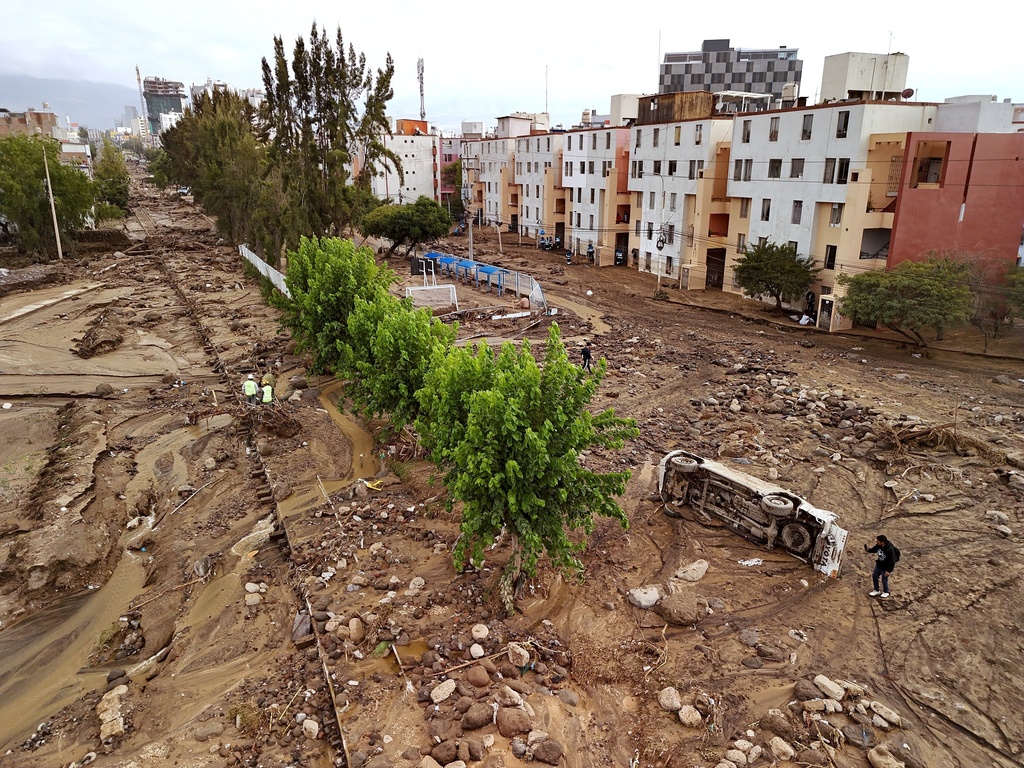 A man takes photos on a destroyed road after heavy rain triggered flooding in Arequipa, Peru, Monday, Feb. 23, 2026. (AP Photo/Jose Sotomayor)