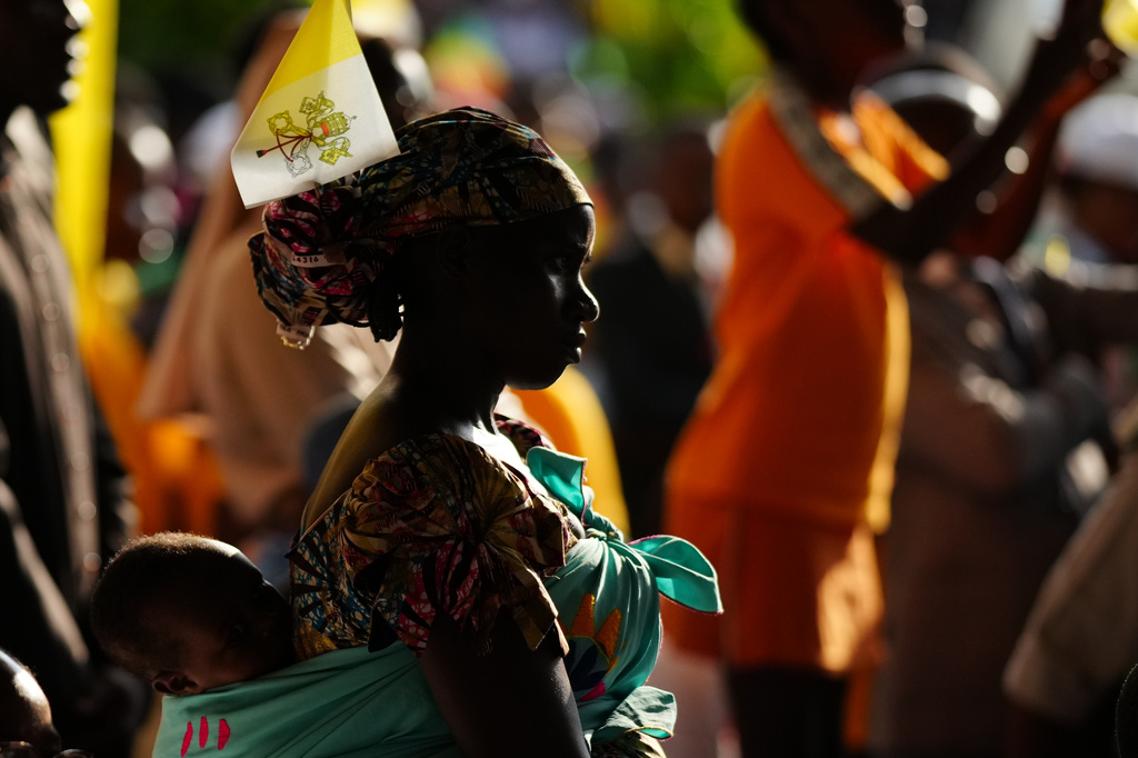 A woman with her child attends Pope Leo XIV's meeting with University students and professors at the Catholic University of Central Africa, in Yaounde Cameroon, Friday, April 17, 2026. (AP Photo/Andrew Medichini)