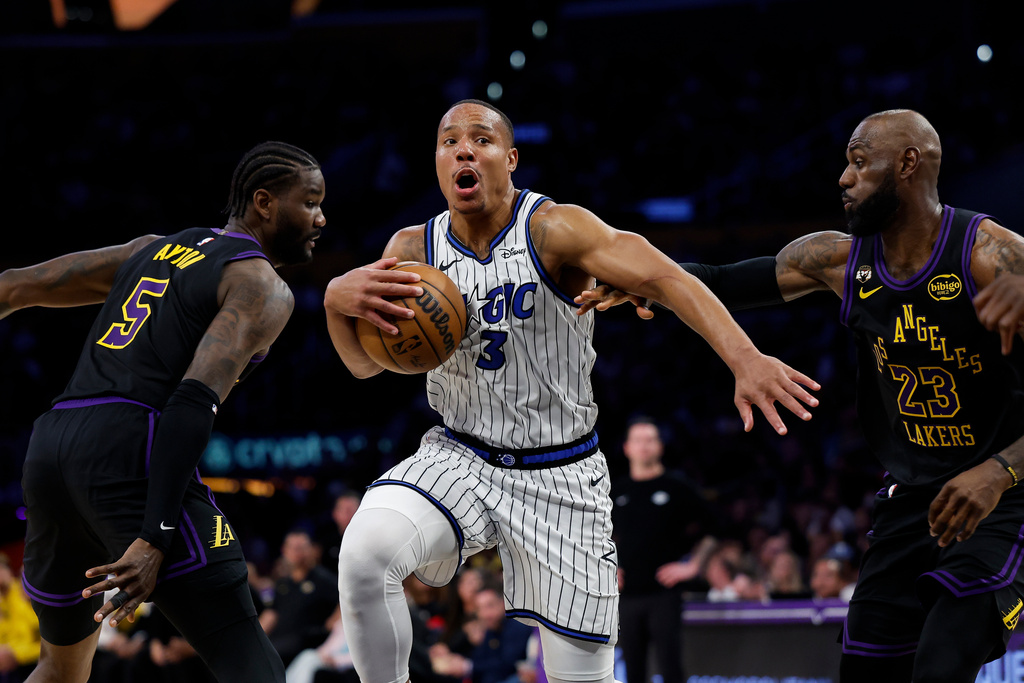 Orlando Magic guard Desmond Bane (3) dribbles with the ball past Los Angeles Lakers center Deandre Ayton (5) and Los Angeles Lakers forward LeBron James (23) during the first half of an NBA basketball game, Tuesday, Feb. 24, 2026, in Los Angeles. (AP Photo/Caroline Brehman)