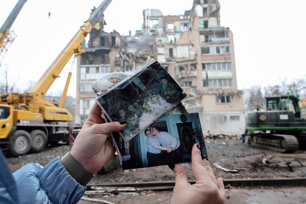 A woman looks on family photographs in front of a residential building which was heavily damaged by a Russian strike on Ternopil, Ukraine, Friday, Nov. 21, 2025. (AP Photo/Vlad Kravchuk)