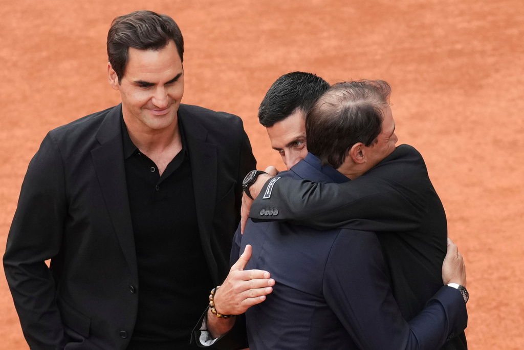 FILE - Rafa Nadal, second right, is hugged by Novak Djokovic as Roger Federer, left, look at them, during a farewell ceremony at center court Philippe-Chatrier, at the Roland-Garros stadium, in Paris, May 25, 2025. (AP Photo/Christophe Ena, file)