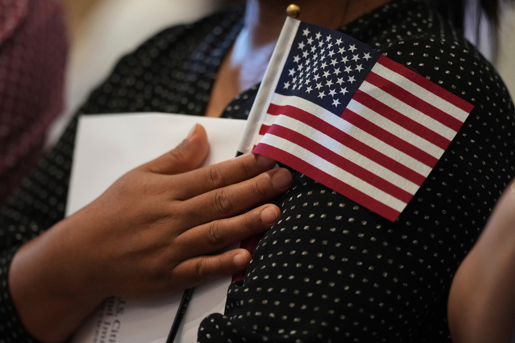 FILE - A woman clutches a U.S. flag as she and applicants from other countries prepare to take the oath of citizenship in commemoration of Independence Day during a Naturalization Ceremony in San Antonio, July 3, 2025. (AP Photo/Eric Gay, File)