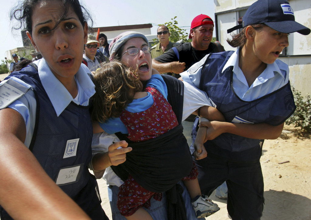FILE - Israeli security forces carry a resisting settler, with her daughter clinging on, to a waiting bus as settlers are evacuated, Aug. 17, 2005 from the Kerem Atzmona settlement in the Gaza Strip. (AP Photo/David Silverman, Pool, File)