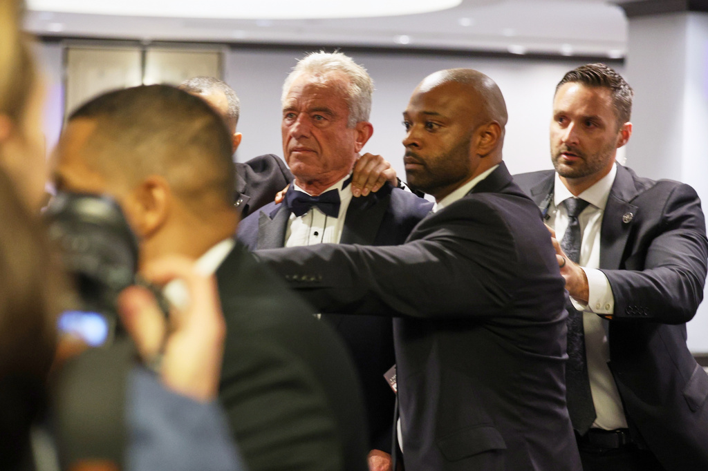 Security rapidly escort Secretary of Health and Human Services Robert F. Kennedy, Jr. out during the White House Correspondents Dinner, Saturday, April 25, 2026, in Washington. (AP Photo/Tom Brenner)