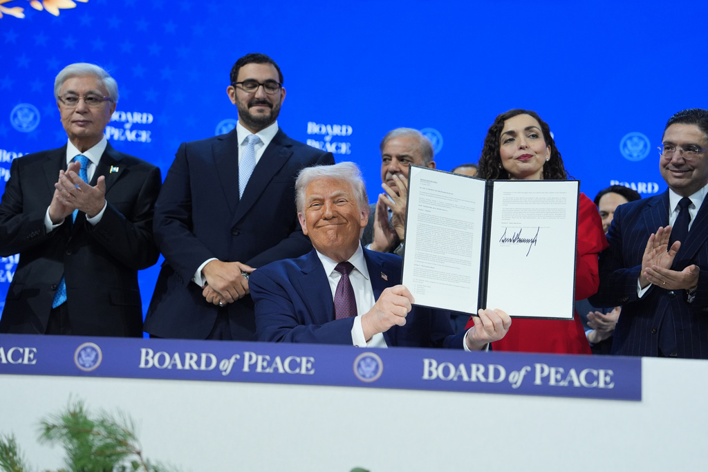 President Donald Trump, center, holds up a signed Board of Peace charter during the Annual Meeting of the World Economic Forum in Davos, Switzerland, Thursday, Jan. 22, 2026. (AP Photo/Evan Vucci)