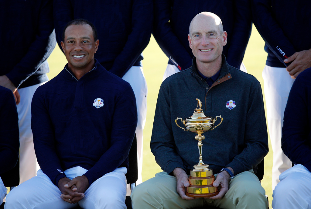 FILE - US team captain Jim Furyk, holding the trophy, and Tiger Woods pose for a photo during the US Ryder Cup team photo call at Le Golf National in Saint-Quentin-en-Yvelines, outside Paris, France, Wednesday, Sept. 26, 2018. (AP Photo/Francois Mori, file)