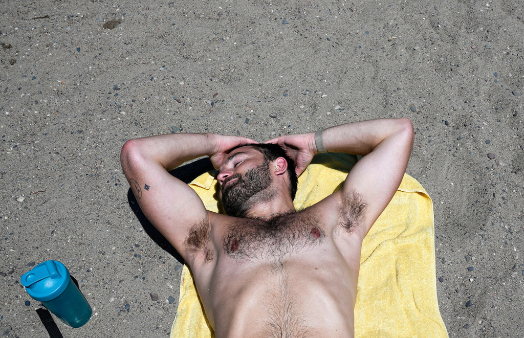 Jack Scheck, of Minneapolis, lays in the sand after a run during an extreme heat warning, Monday, July 13, 2026, in Minneapolis. (AP Photo/Ellen Schmidt)