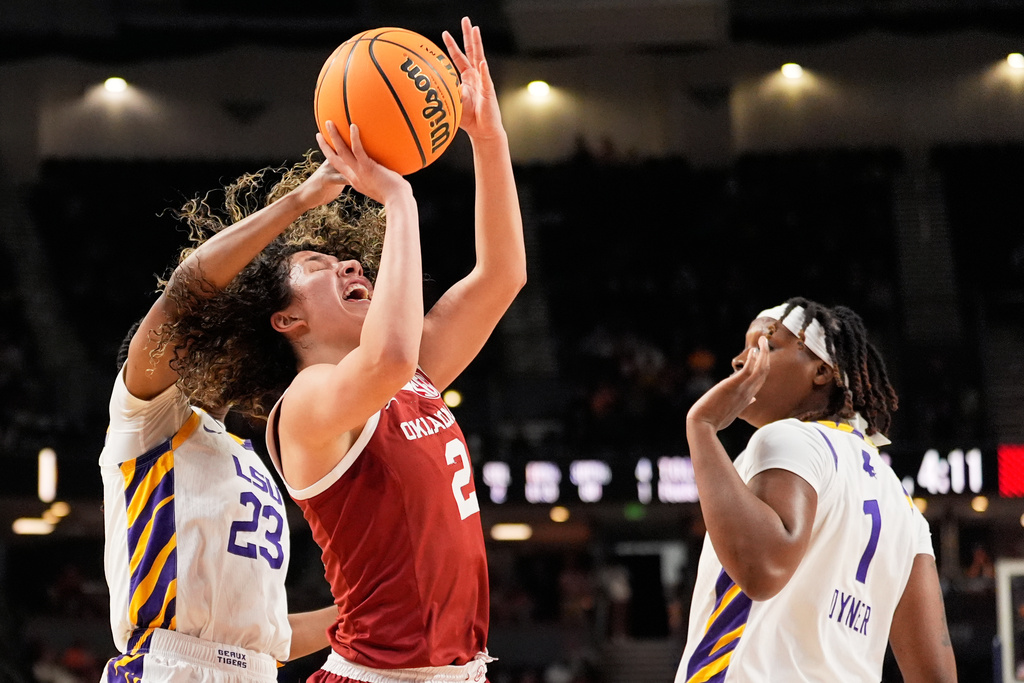 Oklahoma guard Aaliyah Chavez shoots between LSU guard Milaysia Fulwiley and forward Amiya Joyner during first half of an NCAA college basketball game in the quarterfinals of the Southeastern Conference tournament, Friday, March 6, 2026, in Greenville, S.C. (AP Photo/Chris Carlson)
