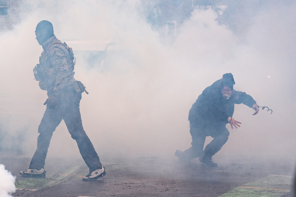 A man arrested by federal agents moments prior escapes in handcuffs after tear gas went off, Wednesday, Jan. 21, 2026, in Minneapolis. (AP Photo/Angelina Katsanis)
