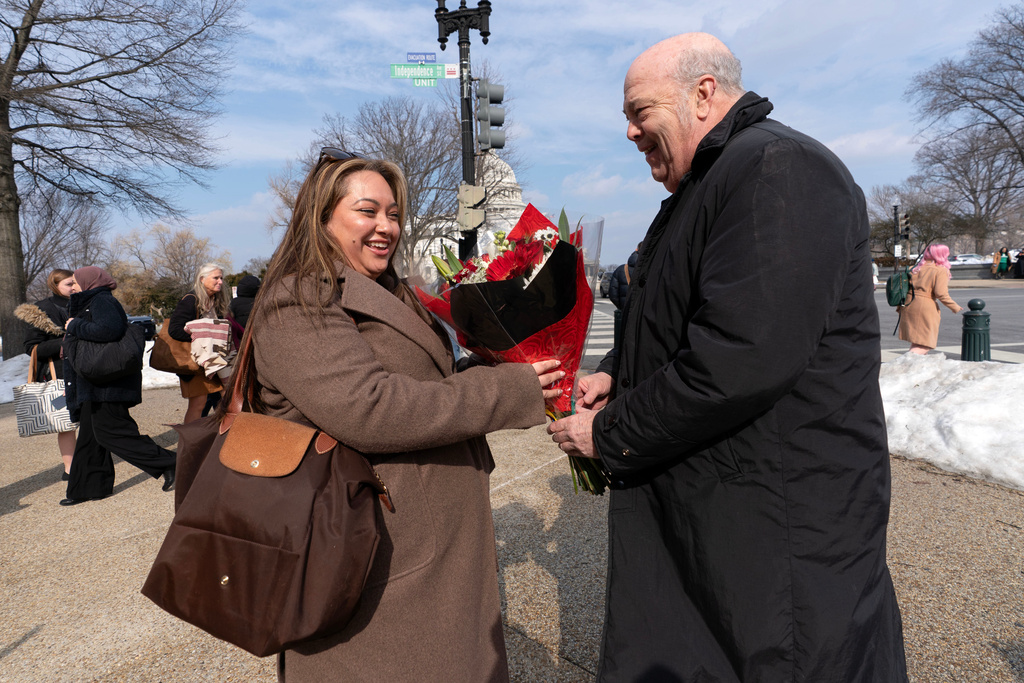 Colombia's Ambassador in the United States Daniel García-Peña, right, hands out flowers from Colombia to pedestrians outside the Longworth House Office Building ahead of Valentine's Day, as a symbol of the close partnership between Colombia and the United States, Wednesday, Feb. 11, 2026, on Capitol Hill in Washington. (AP Photo/Jose Luis Magana)