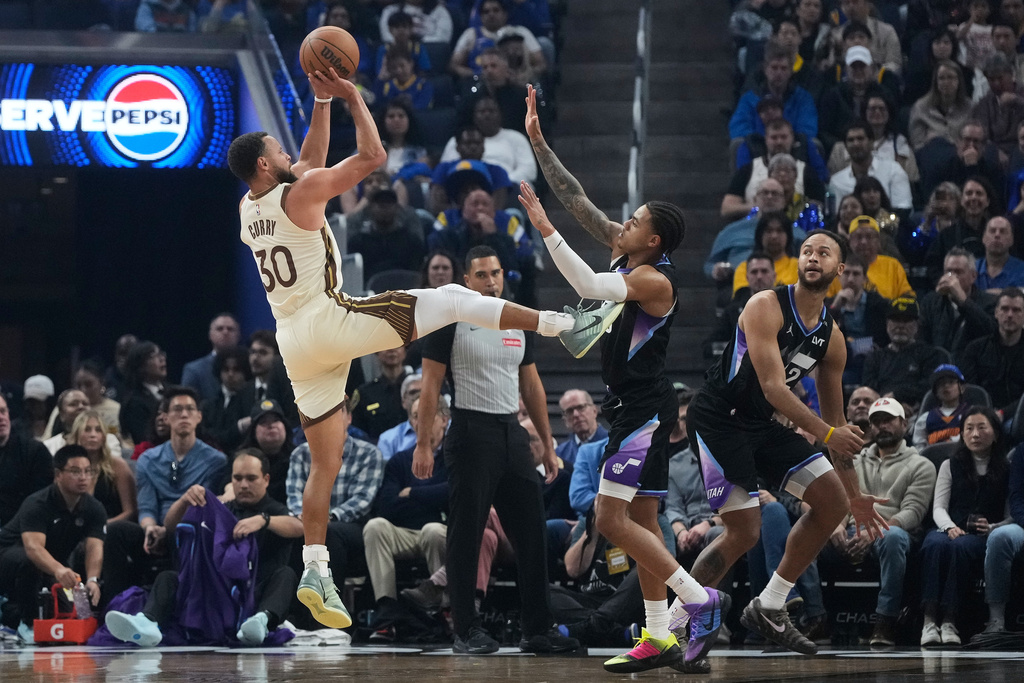 Golden State Warriors guard Stephen Curry (30) shoots against Utah Jazz guard Keyonte George during the first half of an NBA basketball game in San Francisco, Monday, Nov. 24, 2025. (AP Photo/Jeff Chiu)