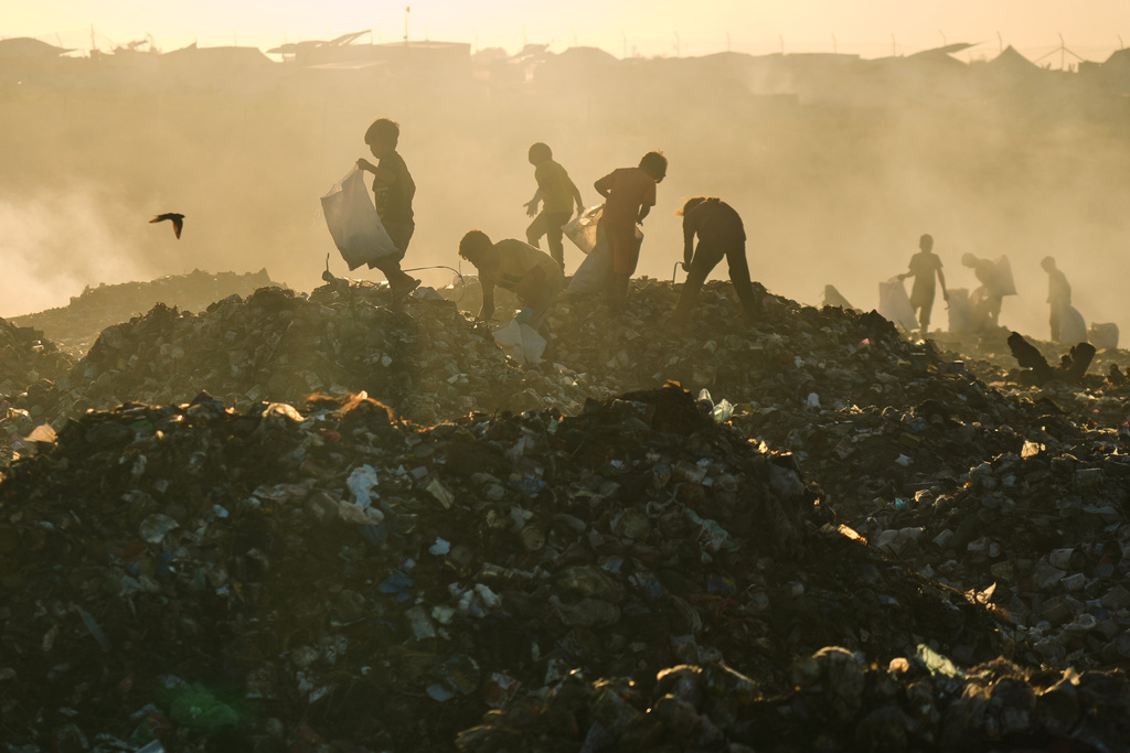 Displaced Palestinian children search for firewood and plastic in a landfill beside the makeshift tent camp where they are taking shelter, in Khan Younis, southern Gaza Strip, Tuesday, Sept. 30, 2025. (AP Photo/Jehad Alshrafi)