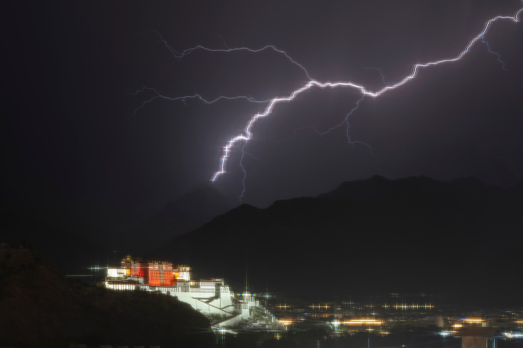A lightning strike flash across the sky near the Potala Palace in Lhasa in western China's Tibet Autonomous Region on Tuesday, July 21, 2026, as seen during a government organized visit for foreign journalists. Starry effect is due to shooting through the net of a window. (AP Photo/Ng Han Guan)