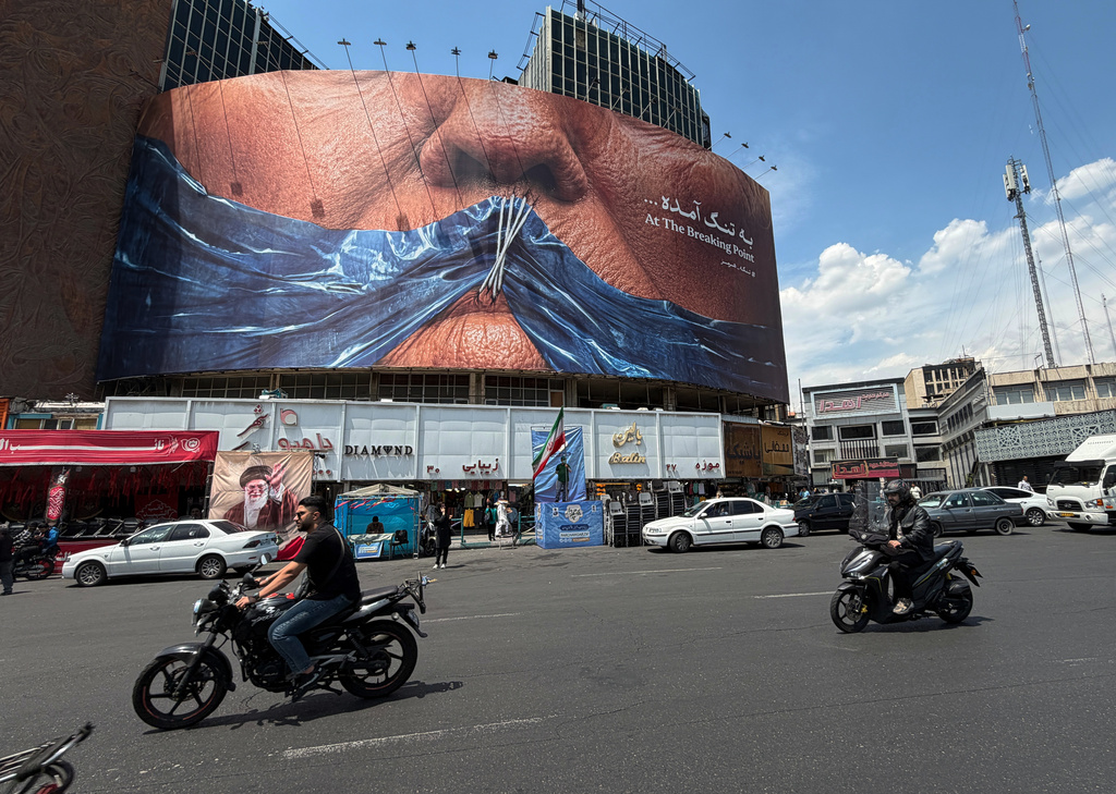Vehicles drive past a billboard with graphic showing Strait of Hormuz and sewn lips of U.S. President Donald Trump in a square in downtown Tehran, Iran, Saturday, May 2, 2026. (AP Photo/Vahid Salemi)