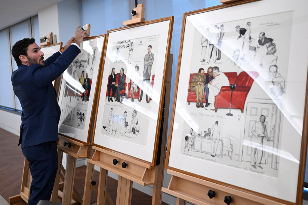 Luke Boorady, of the White House Historical Association, arranges a suite of four inter-related paintings by Norman Rockwell, "So You Want to See the President!" at the association's offices Wednesday, June 10, 2026, in Washington. (AP Photo/John McDonnell)