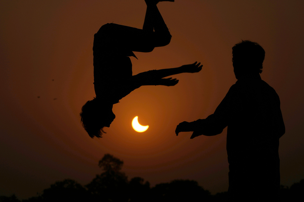 FILE - The partial solar eclipse is framed by youngsters jumping on a trampoline in the outskirts of Lahore, Pakistan, Oct. 25, 2022. (AP Photo/K.M. Chaudary, File)