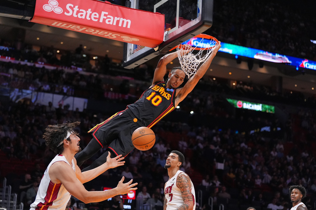 Atlanta Hawks forward Zaccharie Risacher (10) dunks over Miami Heat forward Jaime Jaquez Jr., left as Miami Heat center Kel'el Ware looks on during the first half of an NBA basketball game, Sunday, April 12, 2026, in Miami. (AP Photo/Rebecca Blackwell)
