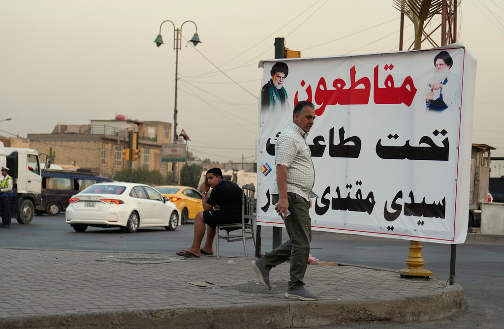 A local walks past a banner calling for a boycott of the elections in Sadr City on the outskirts of Baghdad, Oct. 17, 2025. (AP Photo/Hadi Mizban)