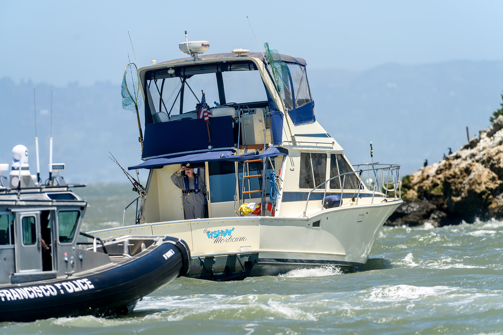 A police boat assists the vessel Fishin' Mortician, stuck on Alcatraz Island's underwater rocks, on Wednesday, July 15, 2026, in San Francisco. (AP Photo/Noah Berger)