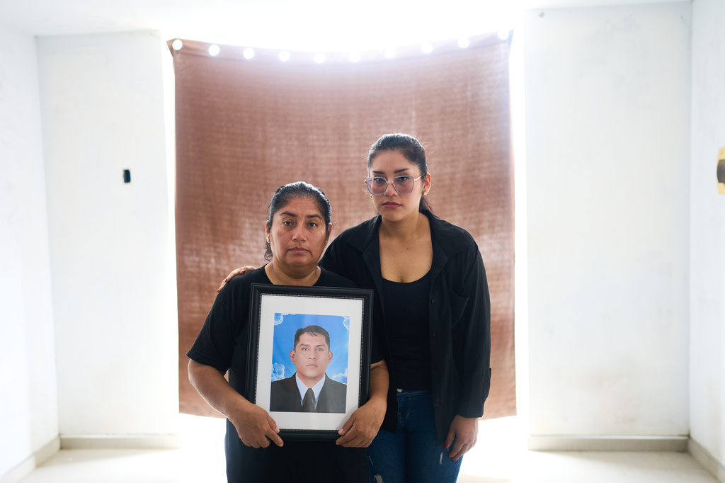 Diane Aguilar, left, and her daughter Perla pose for a photograph with a portrait of Aguilar's husband, Oscar Lavado, who was killed by hitmen on motorbike as he was driving his car weeks earlier, in Trujillo, Peru, Sunday, May 17, 2026. (AP Photo/Rodrigo Abd)