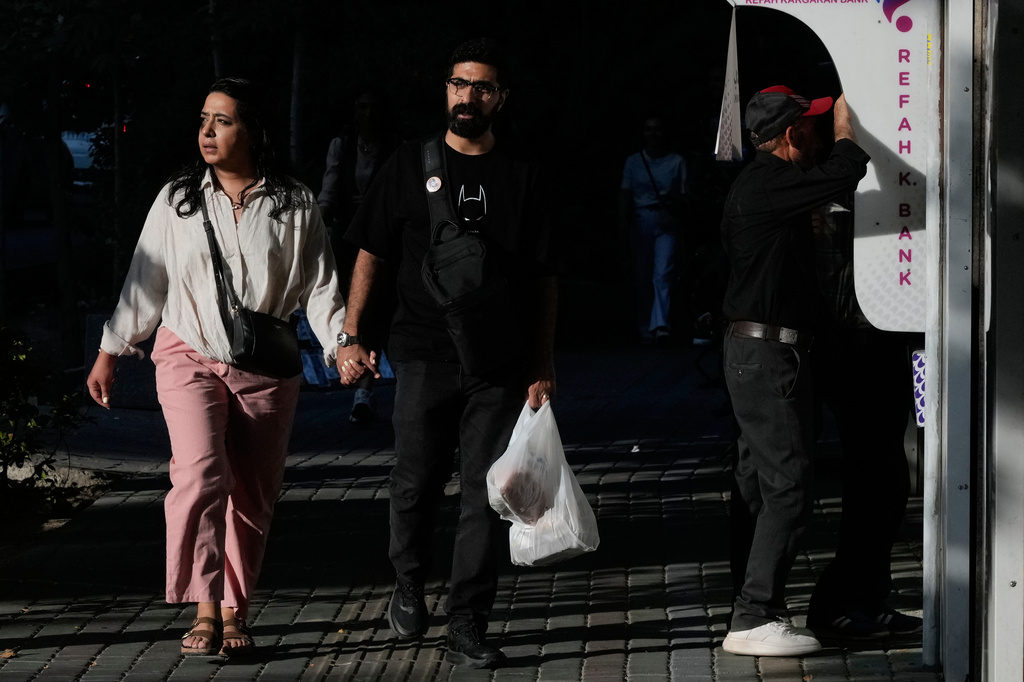 People walk on a sidewalk in northern Tehran, Iran, Thursday, Aug. 13, 2026. (AP Photo/Vahid Salemi)
