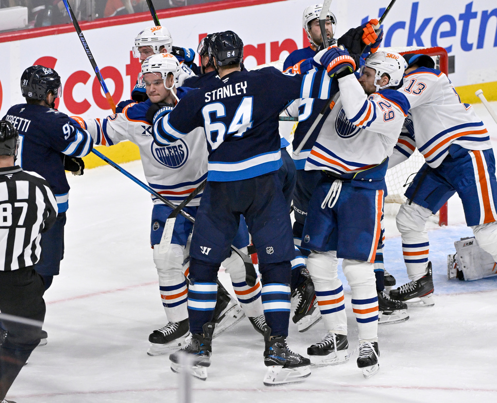 Winnipeg Jets' Logan Stanley (64) grabs Edmonton Oilers' Vasily Podkolzin (92) and Leon Draisaitl (29) after a whistle during the third period of an NHL game in Winnipeg, Monday Dec. 29, 2025. (Fred Greenslade/The Canadian Press via AP)