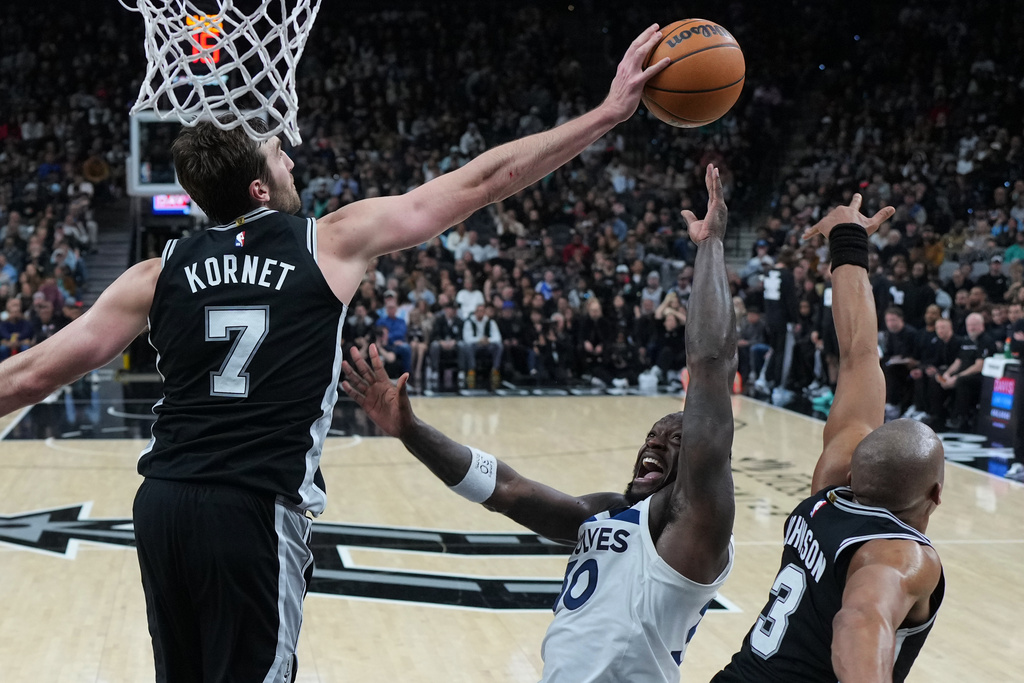 Minnesota Timberwolves forward Julius Randle, center, is blocked by San Antonio Spurs center Luke Kornet (7) during the second half of an NBA basketball game in San Antonio, Saturday, Jan. 17, 2026. (AP Photo/Eric Gay)