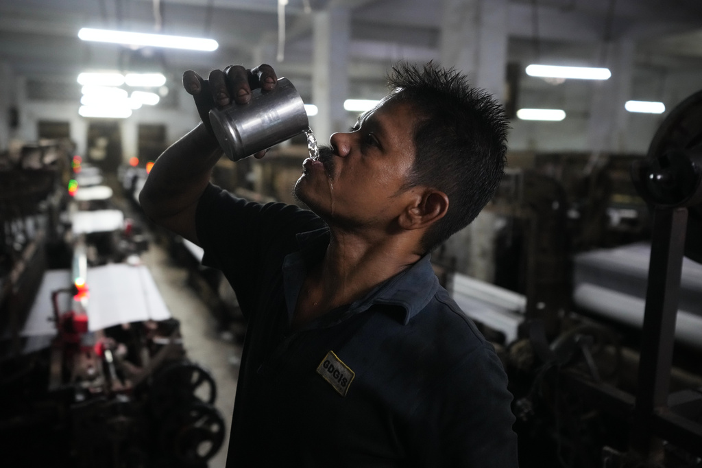 Seemanchal Sahu drinks water as he works at a power loom factory in Surat, India, Wednesday, May 27, 2026. (AP Photo/Ajit Solanki)