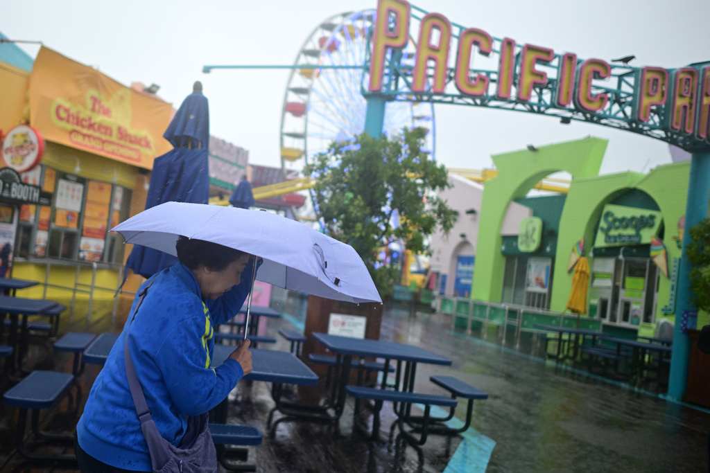 A tourist from China battles the rain on the Santa Monica pier Wednesday, Dec. 24, 2025, in Santa Monica, Calif. (AP Photo/Wally Skalij)