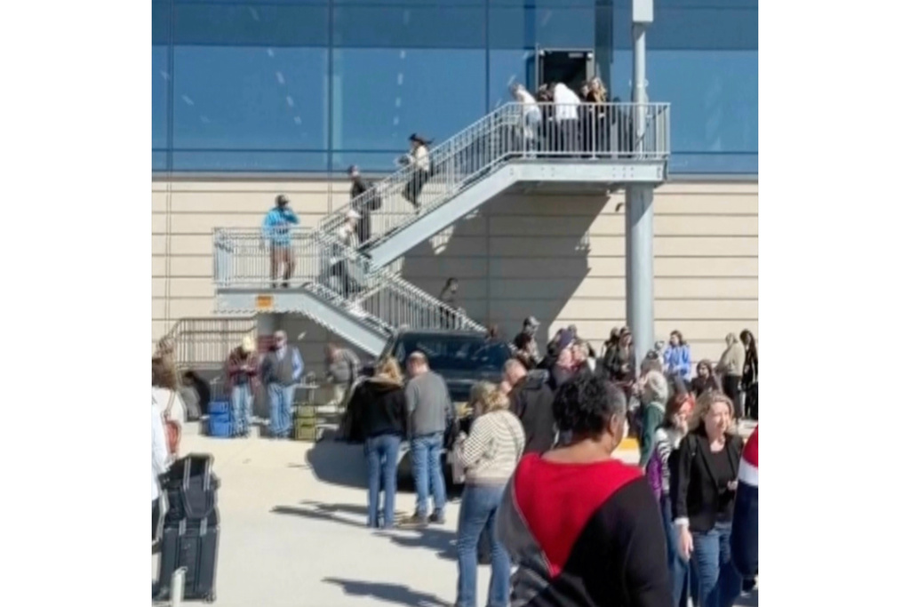 This image taken from video provided by Logan Hawley shows people standing on a tarmac outside of terminals at the Kansas City International Airport in Kansas City, Mo., Sunday, March 8, 2026 (Logan Hawley via AP)