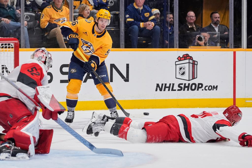 Nashville Predators left wing Erik Haula (56) shoots the puck over Carolina Hurricanes defenseman Jaccob Slavin (74) during the second period of an NHL hockey game Wednesday, Dec. 17, 2025, in Nashville, Tenn. (AP Photo/George Walker IV)