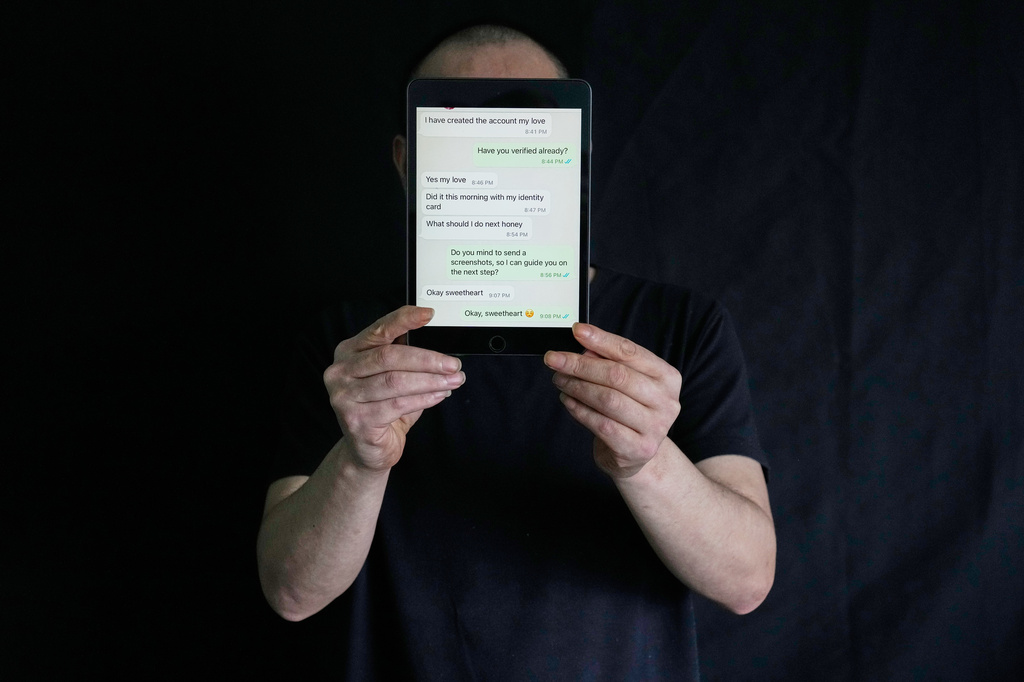 A rescued Chinese scam worker using the pseudonym Wind, part of the condition of interviewing someone serving in the witness protection program for the Philippines authorities, poses with a tablet showing messages he used to scam his victims as he waits to be repatriated at the Presidential Anti-Organized Crime Commission temporary detention center, a former scam compound, in Pasay, Philippines Thursday, June 5, 2025. (AP Photo/Aaron Favila)