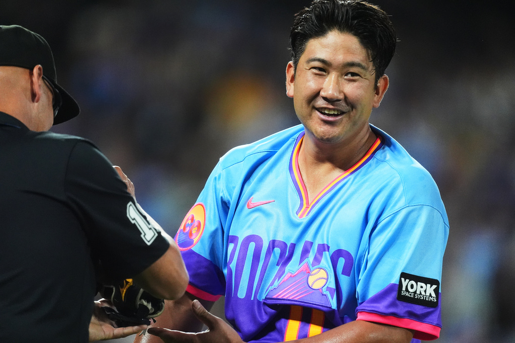 First base umpire Vic Carapazza, left, checks the glove and cap of Colorado Rockies starting pitcher Tomoyuki Sugano after he retired the Kansas City Royals in the fourth inning of a baseball game Friday, July 31, 2026, in Denver. (AP Photo/David Zalubowski)