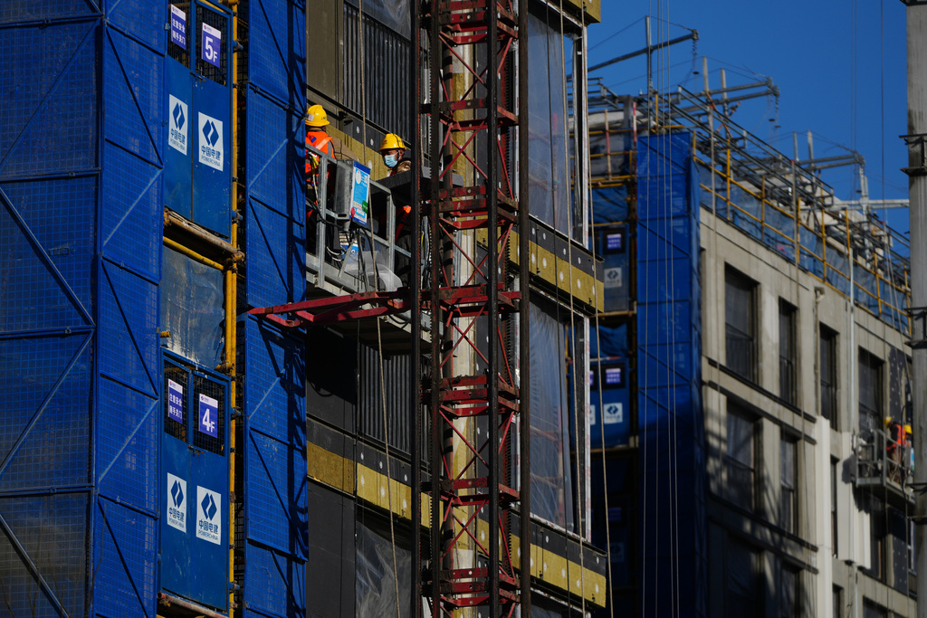 Workers labor on a scaffolding to install insulation layers on a residential building under construction in Beijing on Dec. 3, 2025. (AP Photo/Andy Wong)