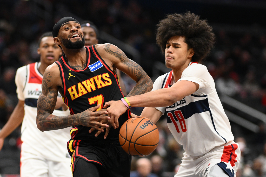 Washington Wizards forward Kyshawn George (18) and Atlanta Hawks guard Nickeil Alexander-Walker, left, battle for the ball during the second half of an NBA basketball game, Saturday, Dec. 6, 2025, in Washington. (AP Photo/Nick Wass)