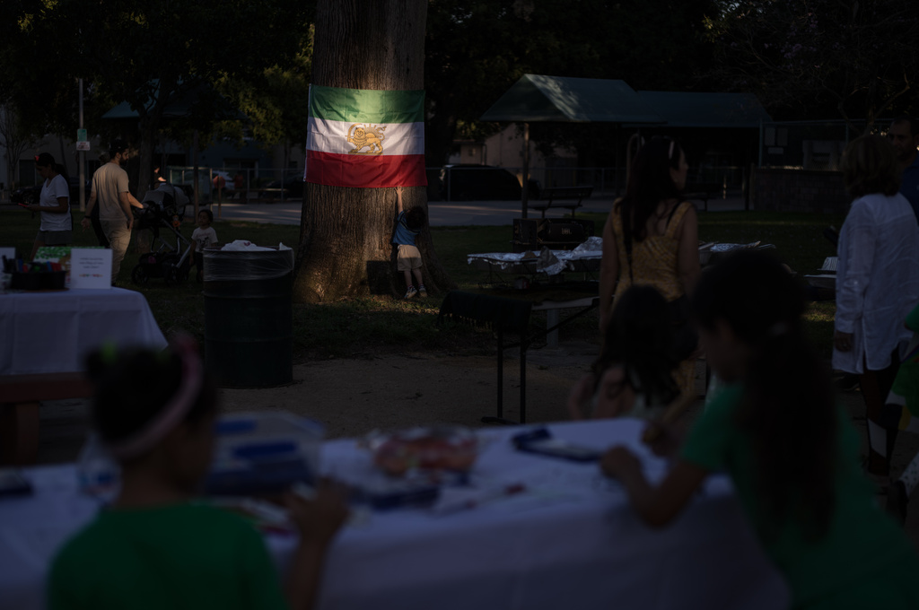 A young boy touches an Iranian flag lit by afternoon sunlight during a community gathering ahead of the Nowruz holiday in the Encino neighborhood of Los Angeles, March 17, 2026. (AP Photo/Jae C. Hong)