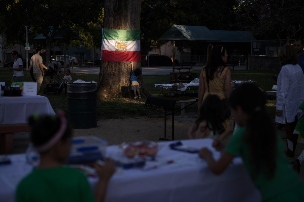 A young boy touches an Iranian flag lit by afternoon sunlight during a community gathering ahead of the Nowruz holiday in the Encino neighborhood of Los Angeles, March 17, 2026. (AP Photo/Jae C. Hong)